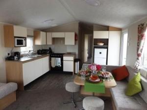 Caravan by the sea Trecco Bay في بورثكول: مطبخ وغرفة معيشة مع طاولة وأريكة
