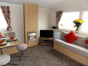 a living room with a couch and a television at Caravan by the sea Trecco Bay in Porthcawl