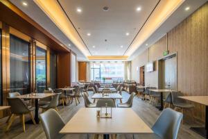 a dining room with tables and chairs in a restaurant at Metropolo Hangzhou West Lake Culture Square in Hangzhou