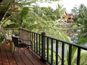 a chair on a deck with a view of a river at Baan Thai House in Phra Nakhon Si Ayutthaya
