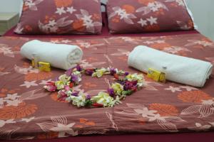 Una cama con dos toallas enrolladas y flores. en Mahana Lodge Hostel & Backpacker, en Papeete