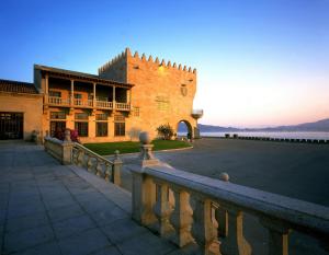 un grande edificio con una recinzione di fronte ad esso di Parador de Baiona a Baiona