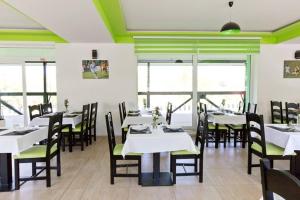 a dining room with white tables and chairs and windows at Reštaurácia GÓL in Veselé