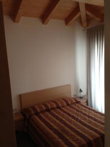 1 dormitorio con cama con edredón y ventana en Residence Antares, en Caorle