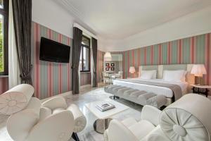 a hotel room with a bed and chairs and a television at Grand Hotel Palace Rome in Rome
