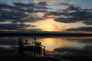 a sunset over a body of water with a dock at Youth Center Vasatokka in Inari