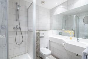 a white bathroom with a shower and a toilet and a sink at Best Western Plus Hotel Excelsior in Erfurt
