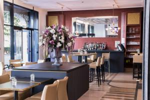 a restaurant with tables and chairs and a counter with flowers at Hotel Art Deco Euralille in Lille