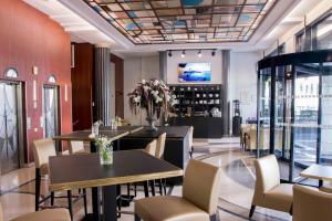 Hotel Art Deco Euralille في ليل: مطعم به طاولات وكراسي وتلفزيون