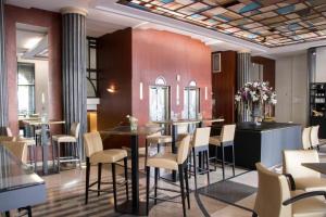 a restaurant with a bar with chairs and tables at Hotel Art Deco Euralille in Lille