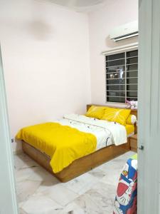 - une chambre avec un lit doté de draps jaunes et une fenêtre dans l'établissement Lot 4 PD Villa, à Port Dickson