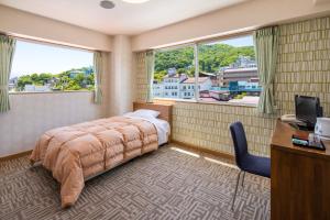 a bedroom with a bed and a desk and two windows at Stay View Ikaho in Shibukawa