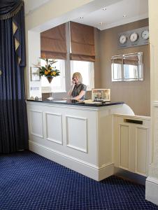 a woman sitting at a counter talking on a cell phone at Devonshire Park Hotel in Eastbourne