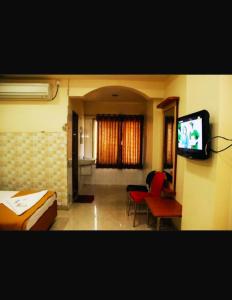 a room with a tv and a couch and chairs at Hotel Apple Sai Residency in Shirdi
