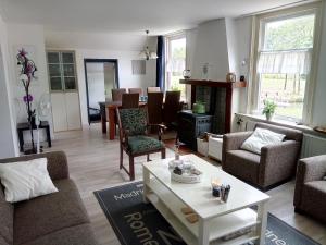 een woonkamer met een bank, stoelen en een tafel bij Breeveld Cottage in Woerden