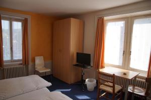 een slaapkamer met een bed, een bureau en een televisie bij Hotel Gotthard in Brugg