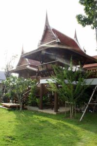 a building with a roof with trees in front of it at Baan Thai House in Phra Nakhon Si Ayutthaya