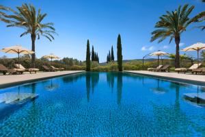 a large swimming pool with palm trees and umbrellas at Torrent Fals in Santa Maria del Camí
