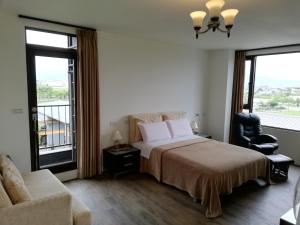 una camera con letto, sedia e finestre di Tata House B&B a Xingjian