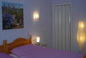 a bedroom with a bed with purple sheets and a lamp at Ferienwohnung Nachbars Garten in Grünendeich