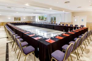 una grande sala banchetti con tavoli e sedie lunghi di Exe Las Adelfas a Cordoba Altre 37 foto