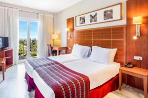 una camera d'albergo con un letto grande e una finestra di Exe Las Adelfas a Cordoba