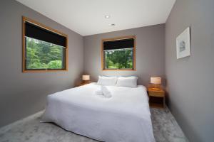 a bedroom with a large white bed with two windows at WAGAYA by Hakuba Hotel Group in Hakuba