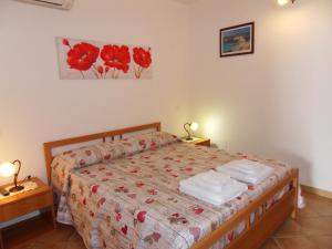 una camera da letto con un letto con fiori rossi di Appartamento Girasole a Lampedusa