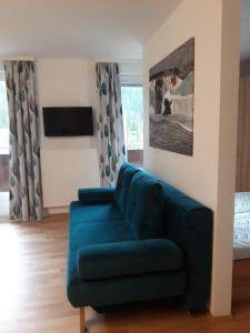 sala de estar con sofá azul y TV en Ferienwohnung Ski-Hans, en Planneralm