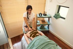 a woman is giving a man a massage at Martinhal Sagres Beach Family Resort Hotel in Sagres