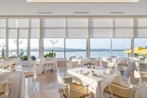 a restaurant with white tables and chairs and large windows at Eurostars Gran Hotel La Toja in Isla de la Toja