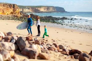 a man and a woman and a child walking on a beach at Martinhal Sagres Beach Family Resort Hotel in Sagres