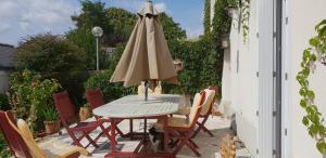 einen Tisch und Stühle mit Sonnenschirm auf einer Terrasse in der Unterkunft Gîte Mido in Cordemais