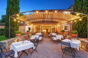 a patio with white tables and chairs and a stone wall at Torrent Fals in Santa Maria del Cam&iacute;