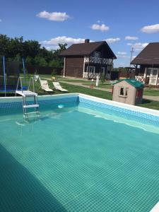 a swimming pool with a chair in front of a house at Ostrivky in Svityazʼ
