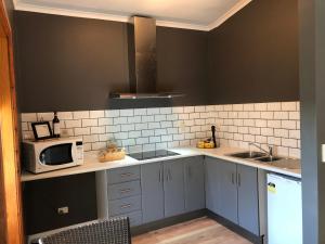 uma cozinha com armários brancos e um micro-ondas em Amande Bed and Breakfast em McLaren Vale