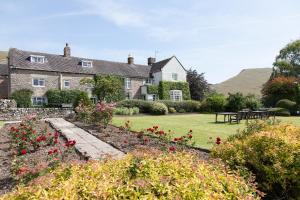 アシュボーンにあるThe Izaak Walton Country House Hotel - Dovedaleの赤い花が咲く庭のある大きな家