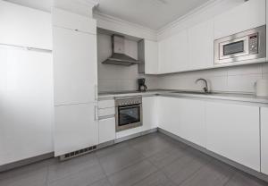 uma cozinha branca com armários brancos e um lavatório em Urumea 4 - Apartamento con parking em San Sebastián
