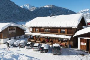 ein schneebedecktes Gebäude mit Autos auf einem Parkplatz in der Unterkunft Ferienbauernhof Moosbrugger in Schoppernau