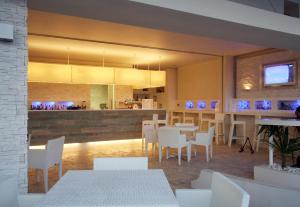 a restaurant with white tables and white chairs at Hotel Village Scoglio Della Galea in Capo Vaticano