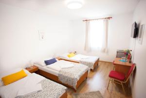 a room with three beds and a chair at Hotel Taxis Bratislava in Bratislava