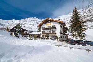 a large building with cars parked in the snow at Hotel Alpenblick in Pfelders