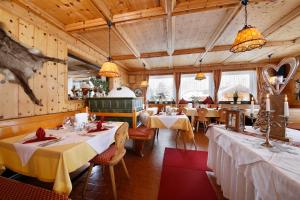 a dining room with tables and chairs and windows at Hotel Alpenblick in Pfelders