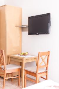 een tafel en stoelen met een televisie aan de muur bij Apartments Valentino in Vodice