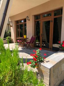 a patio with red flowers and a table and chairs at The Lake Villa in Smolyan