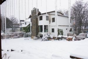 a house with snow on the ground in front of a building at Aves del Sur in Ushuaia