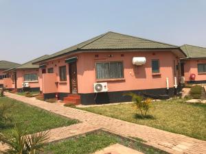 a pink house with a lawn in front of it at Northern Rock Hotel in Mpika