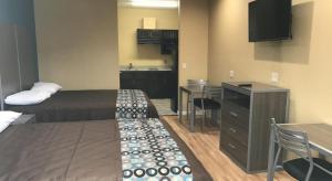 a small hotel room with a bed and a kitchen at Deluxe Inn & Suites - Baytown in Baytown