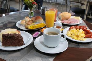 a table with plates of breakfast food and a cup of coffee at Hotel Princeton in Piracicaba