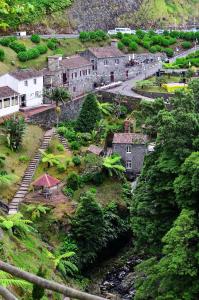 a village on the side of a mountain with a river at Ribeira dos Caldeirões in Achada